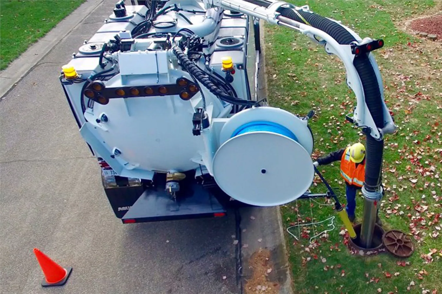 Aquatech combination sewer jetter operating at a roadside, with an operator in safety gear performing sewer cleaning.
